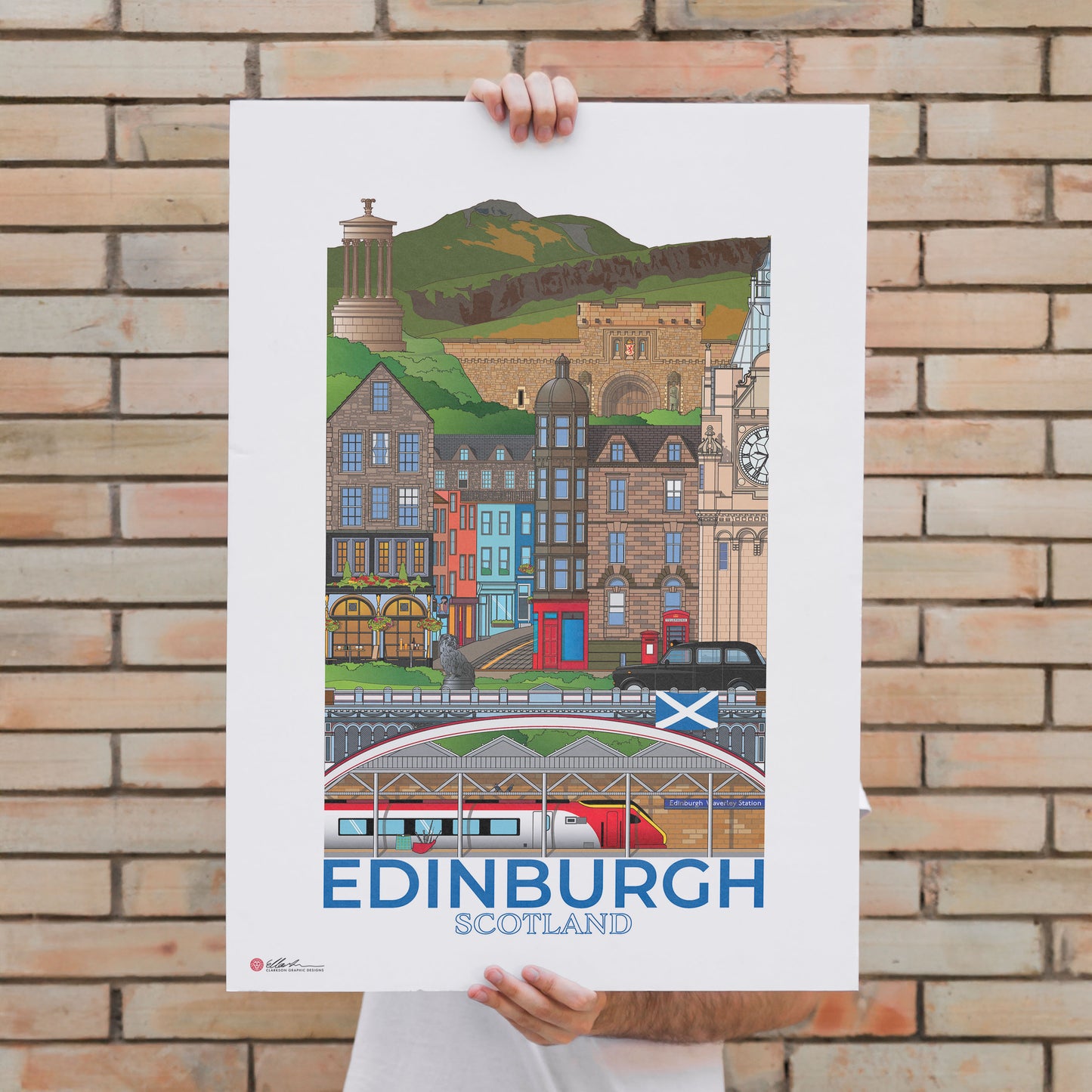 Person holding a poster of Edinburgh, Scotland against a brick wall.