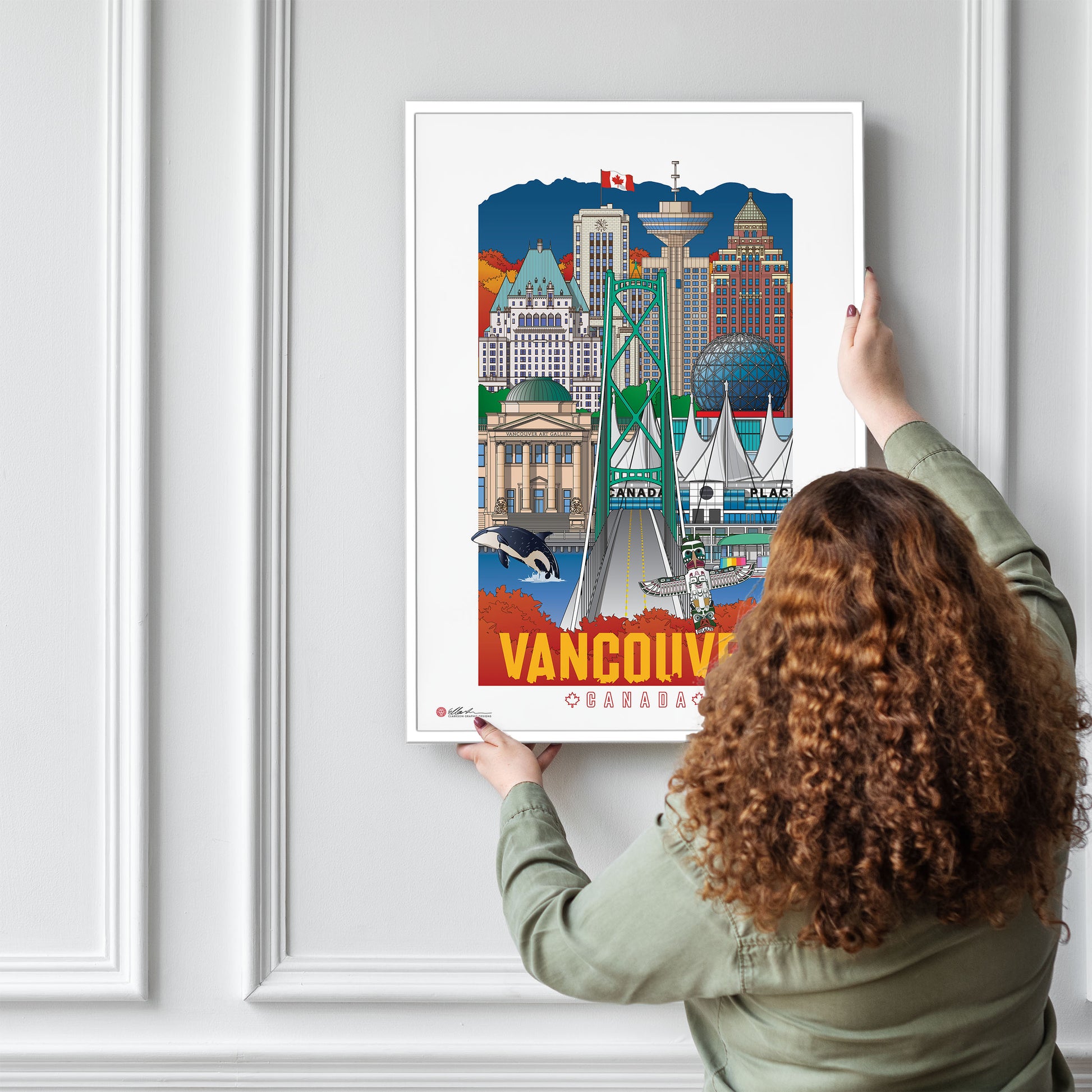 Person hanging a framed poster of Vancouver on a wall