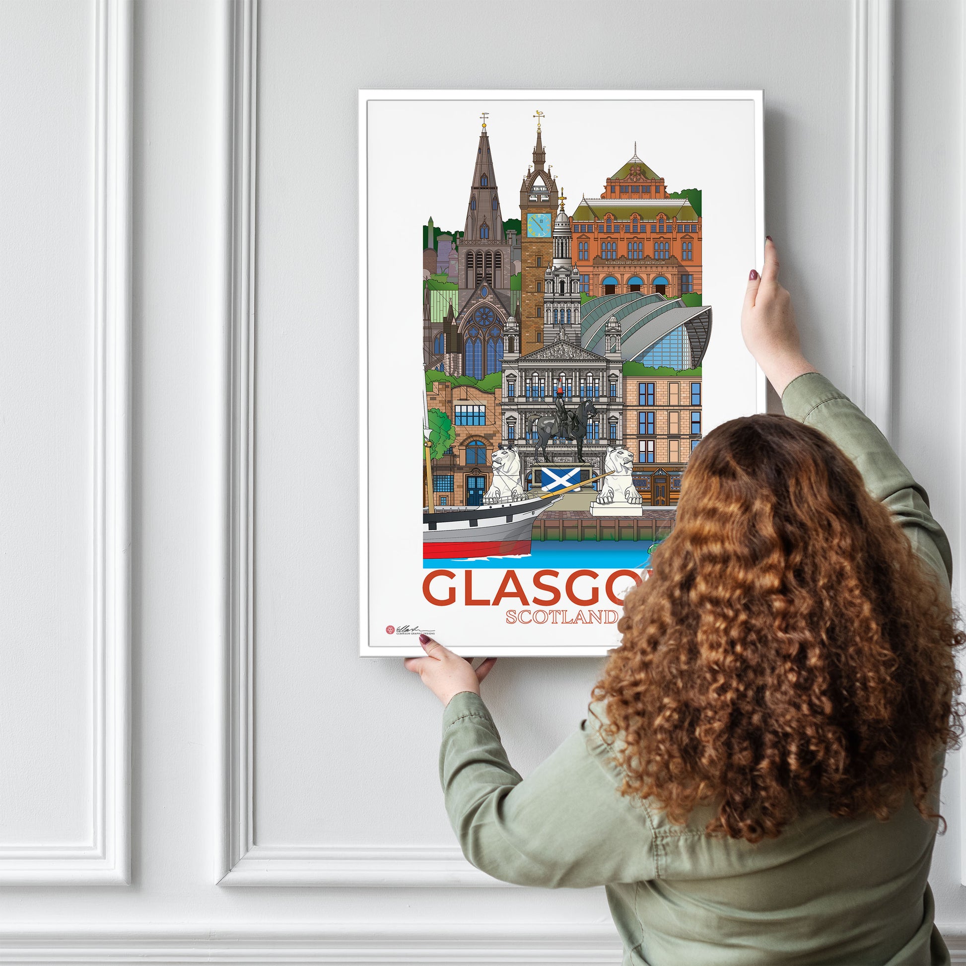 Person hanging a poster of Glasgow, Scotland on a wall.